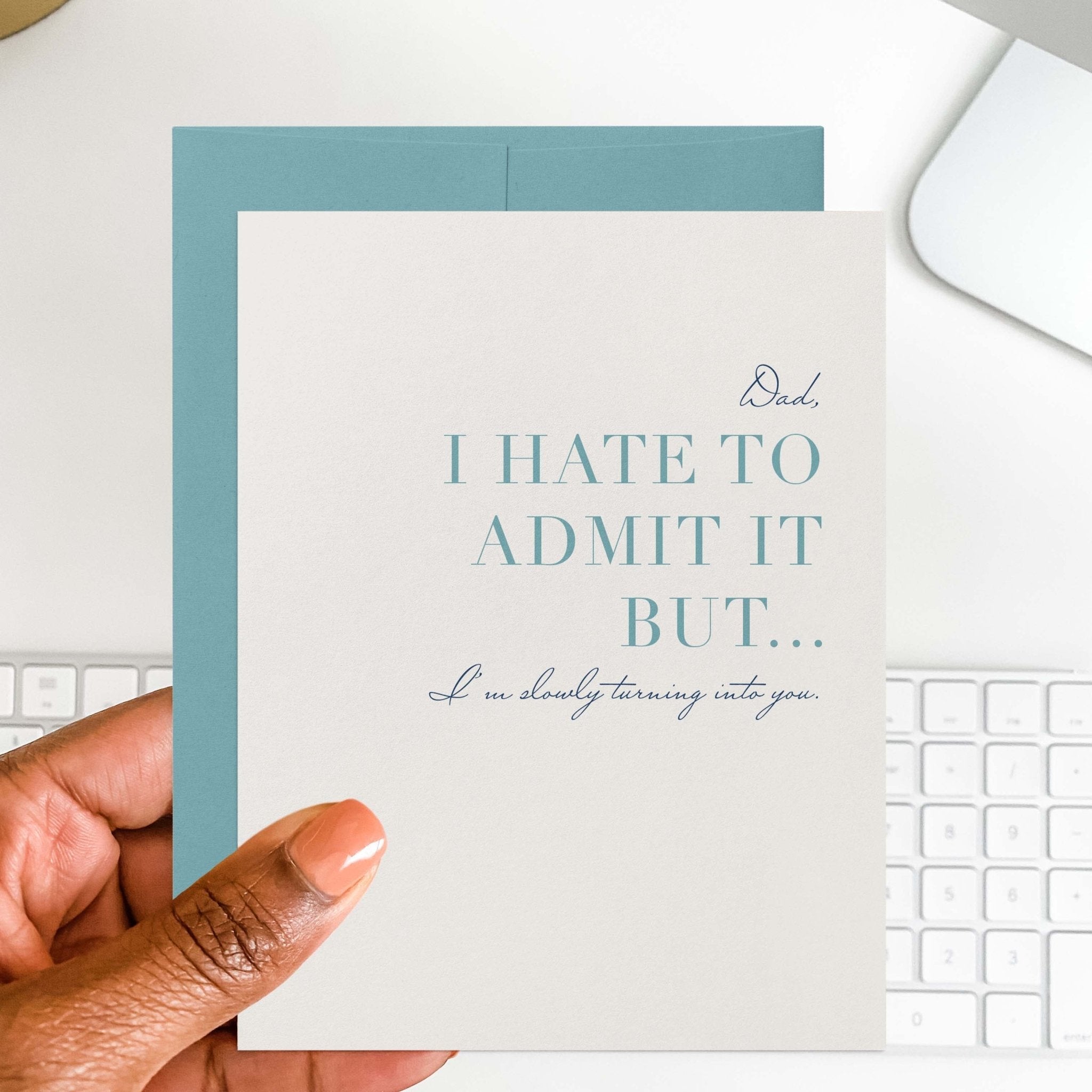 Hate to Admit It funny Father's Day card by Blú Rose held in hand over a white desk with keyboard and blue envelope