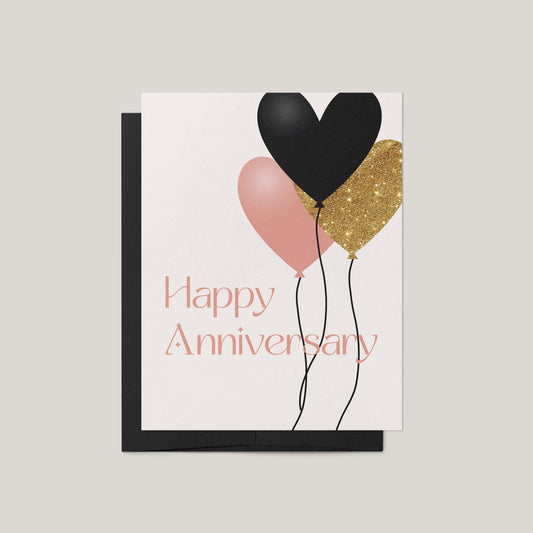 Greeting card with black, pink, and gold balloons and 'Happy Anniversary' text on a light gray background.