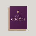 Holiday Cheers greeting card by Blú Rose, deep plum card with gold champagne flutes and holiday cheers text, shown with kraft envelope