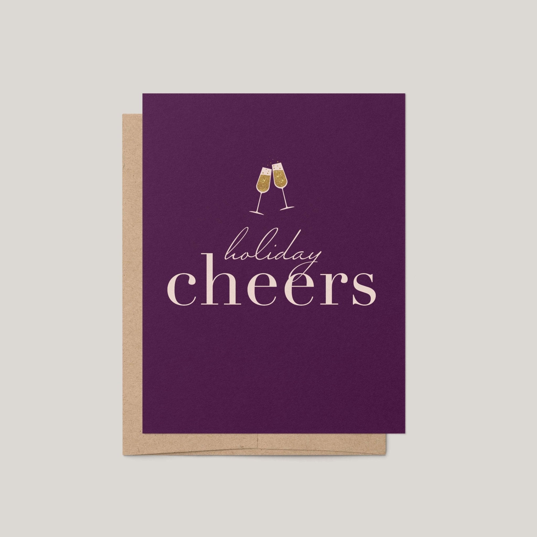 Holiday Cheers greeting card by Blú Rose, deep plum card with gold champagne flutes and holiday cheers text, shown with kraft envelope