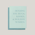 Hugs, Kisses & Holiday Wishes greeting card by Blú Rose, sage green card with tonal serif text, shown with matching green envelope