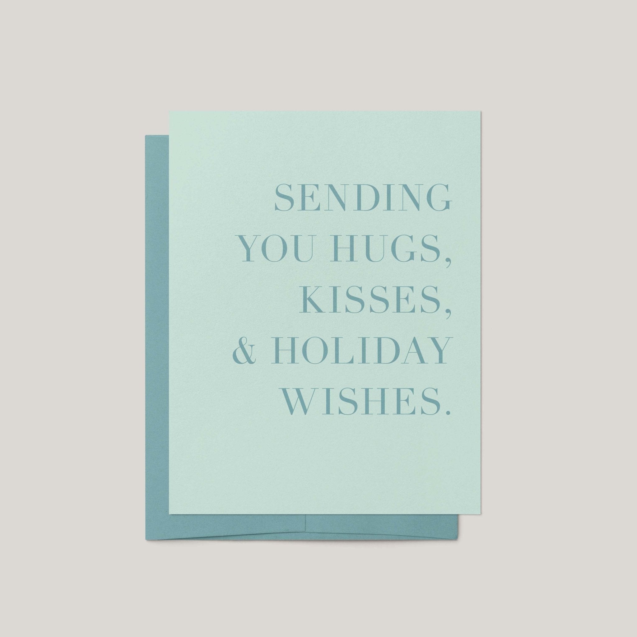 Hugs, Kisses & Holiday Wishes greeting card by Blú Rose, sage green card with tonal serif text, shown with matching green envelope
