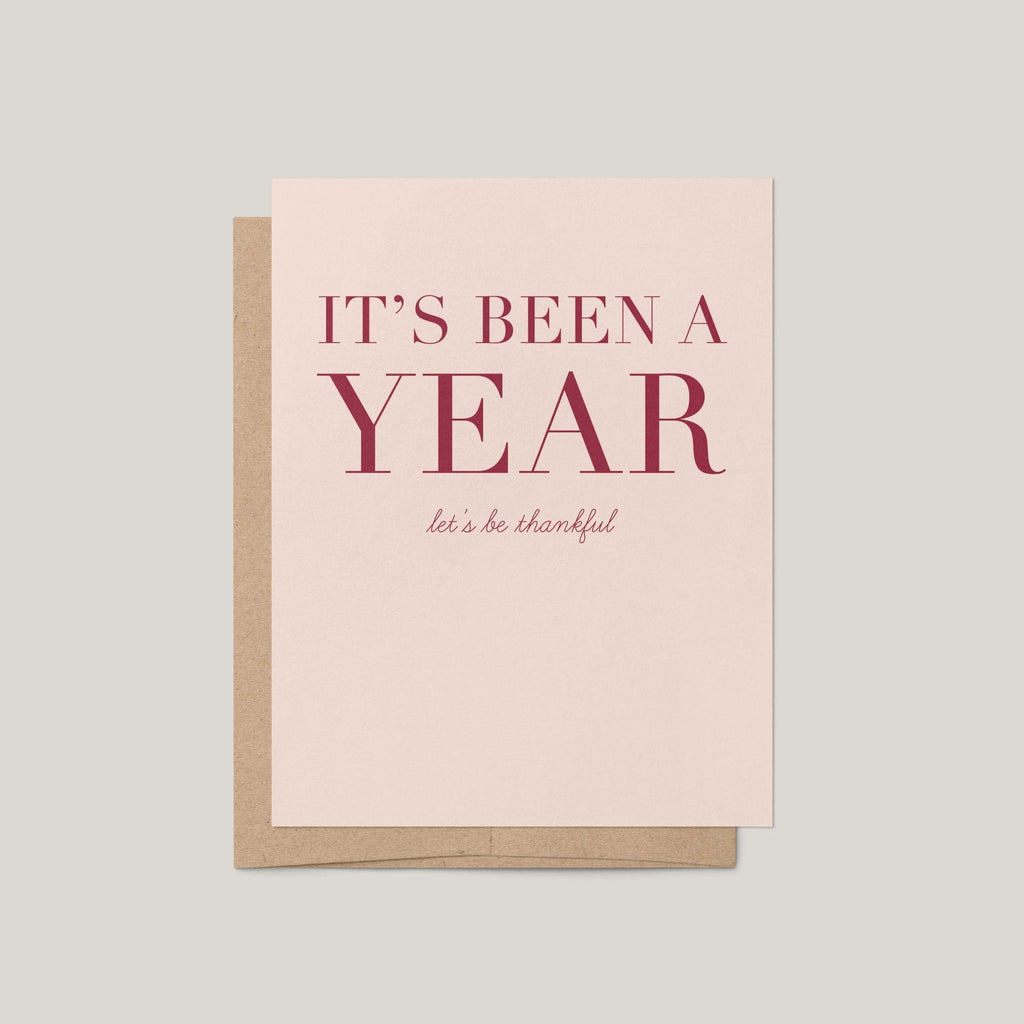 It's Been a Year Thanksgiving greeting card by Blú Rose, blush card with burgundy serif text, shown with kraft envelope
