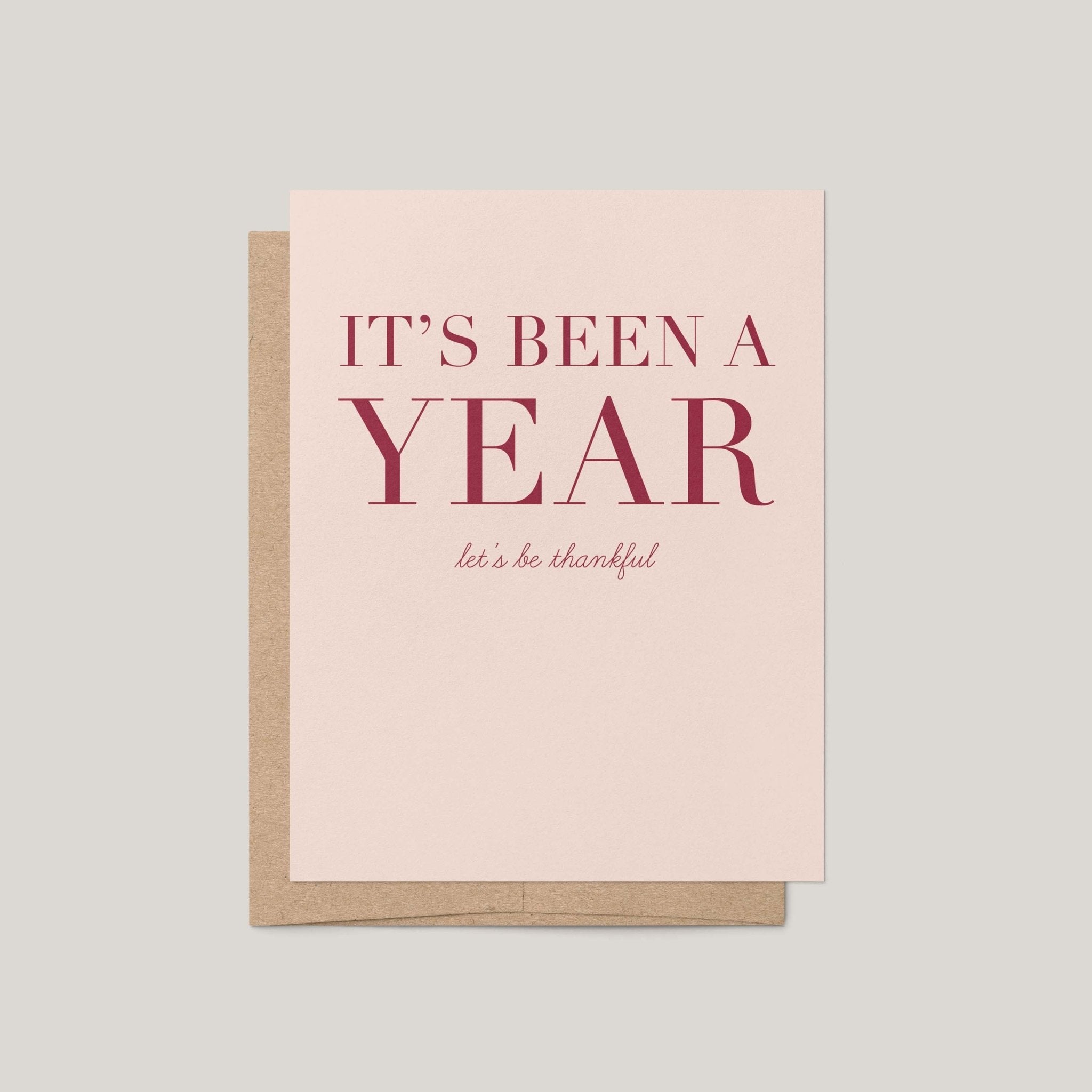 It's Been a Year Thanksgiving greeting card by Blú Rose, blush card with burgundy serif text, shown with kraft envelope
