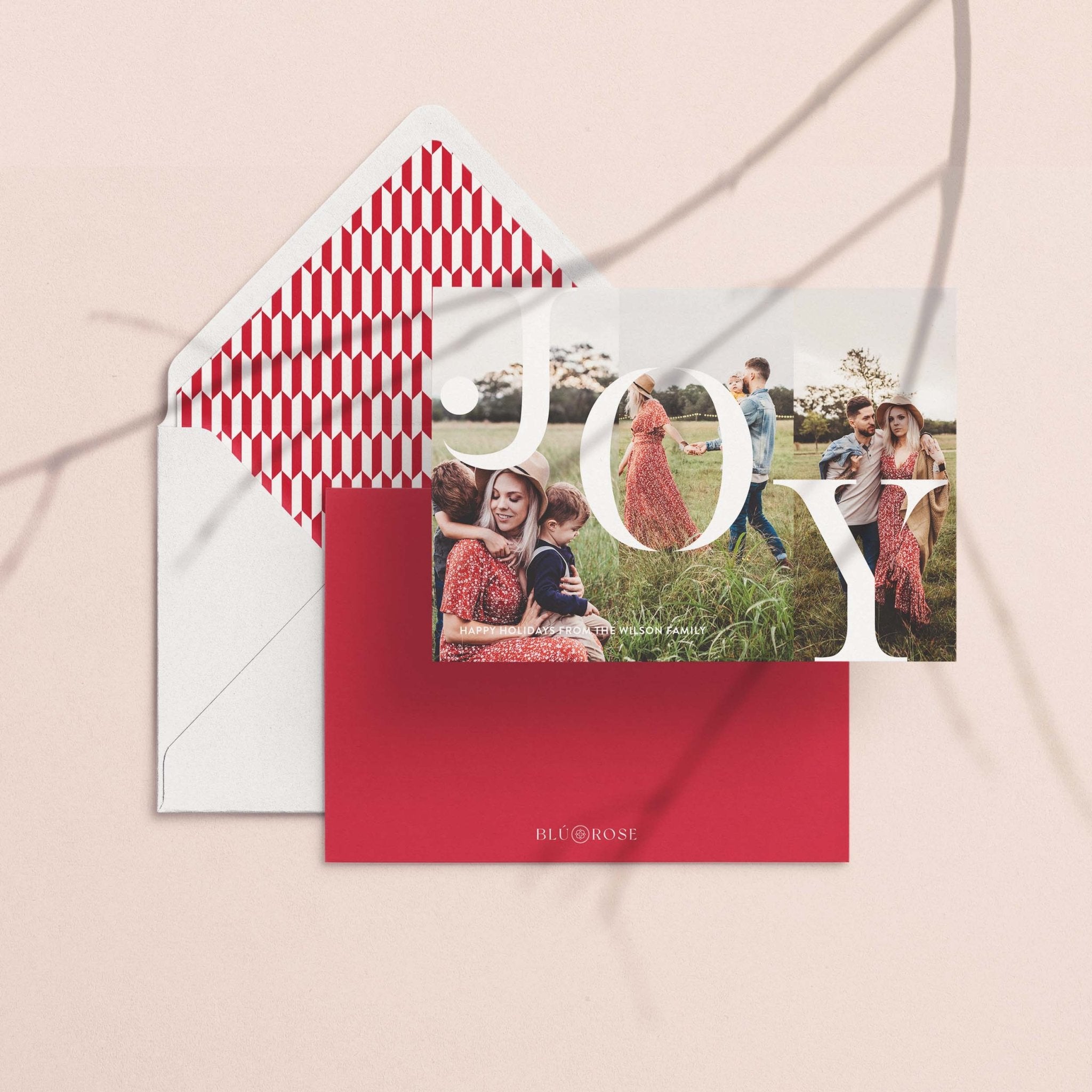 Joy card with its red zigzag envelope liner styled on a blush backdrop