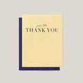 A yellow-colored thank-you card with navy blue text reading 'just a little THANK YOU', shown with a matching navy blue envelope on a light gray background.