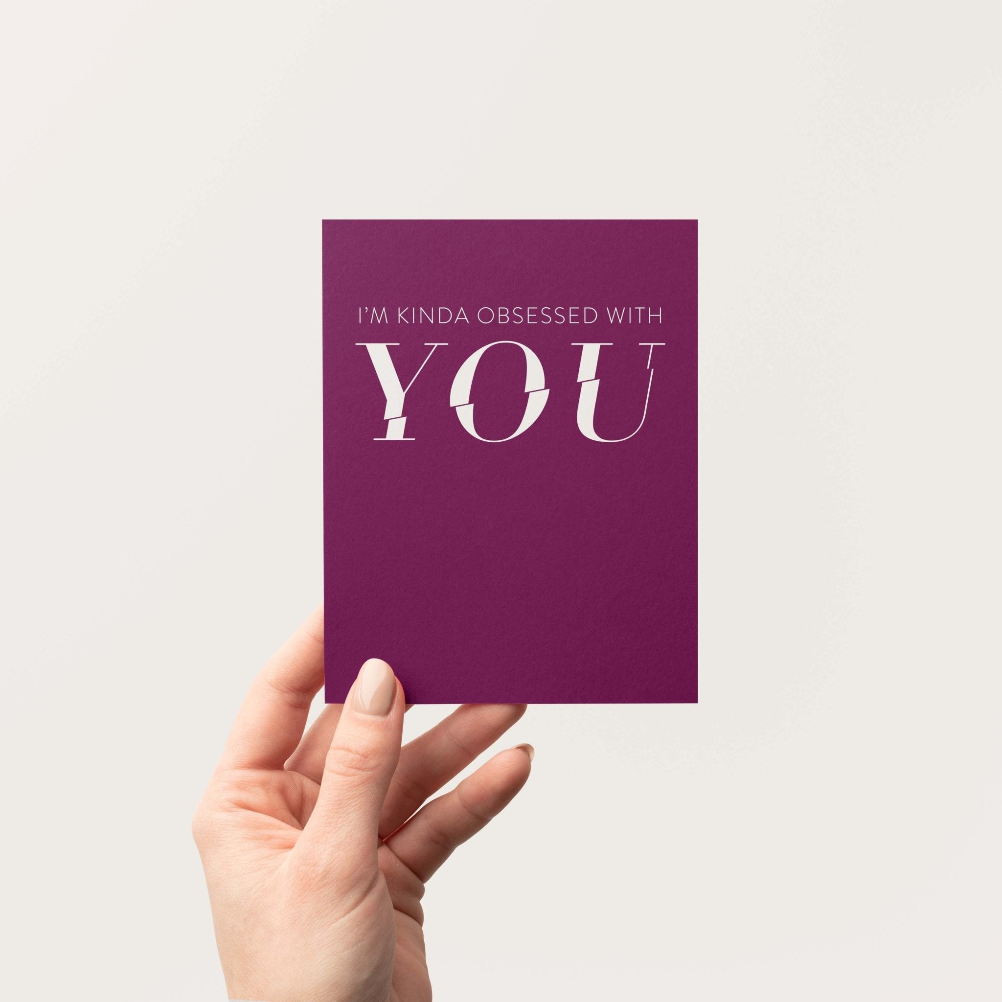 Kinda Obsessed greeting card by Blú Rose held in hand against a neutral off-white background