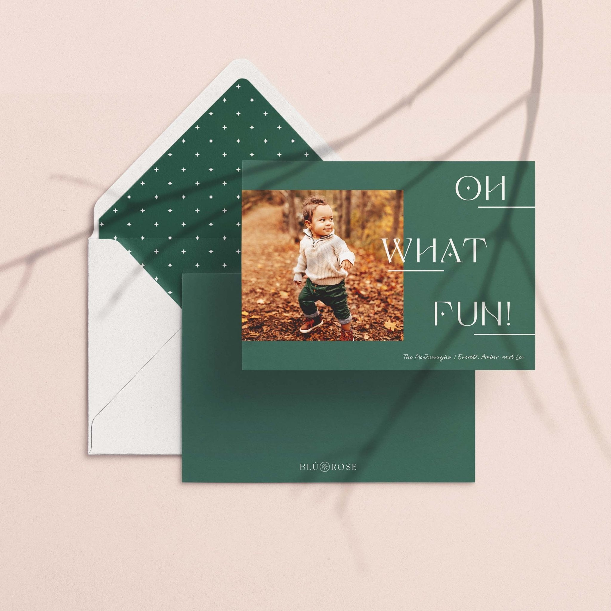 Left Photo card with its forest green dotted envelope liner styled on a blush backdrop