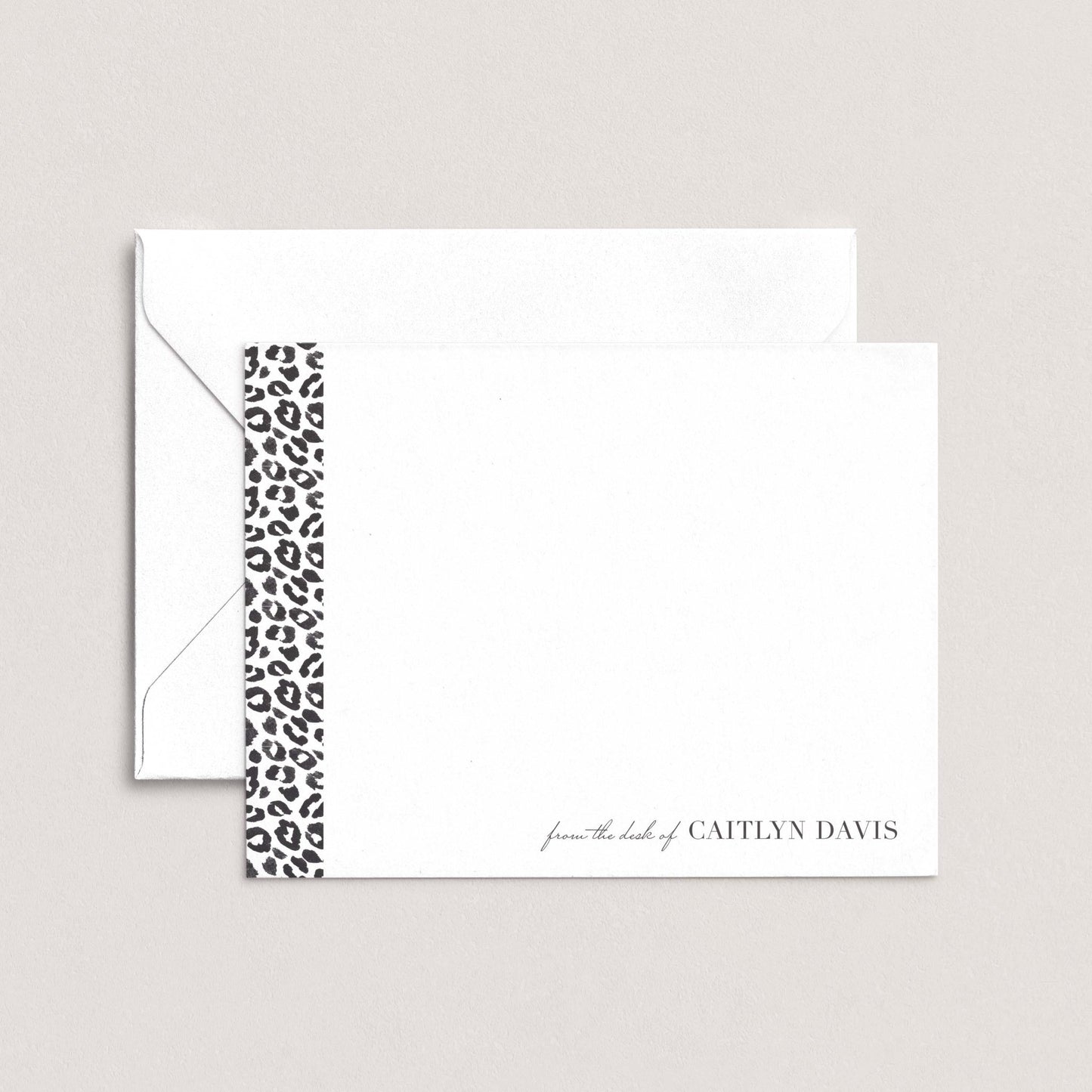 A white envelope with a black and white leopard print border, and a blank card with the name 'Caitlyn Davis' printed on it.