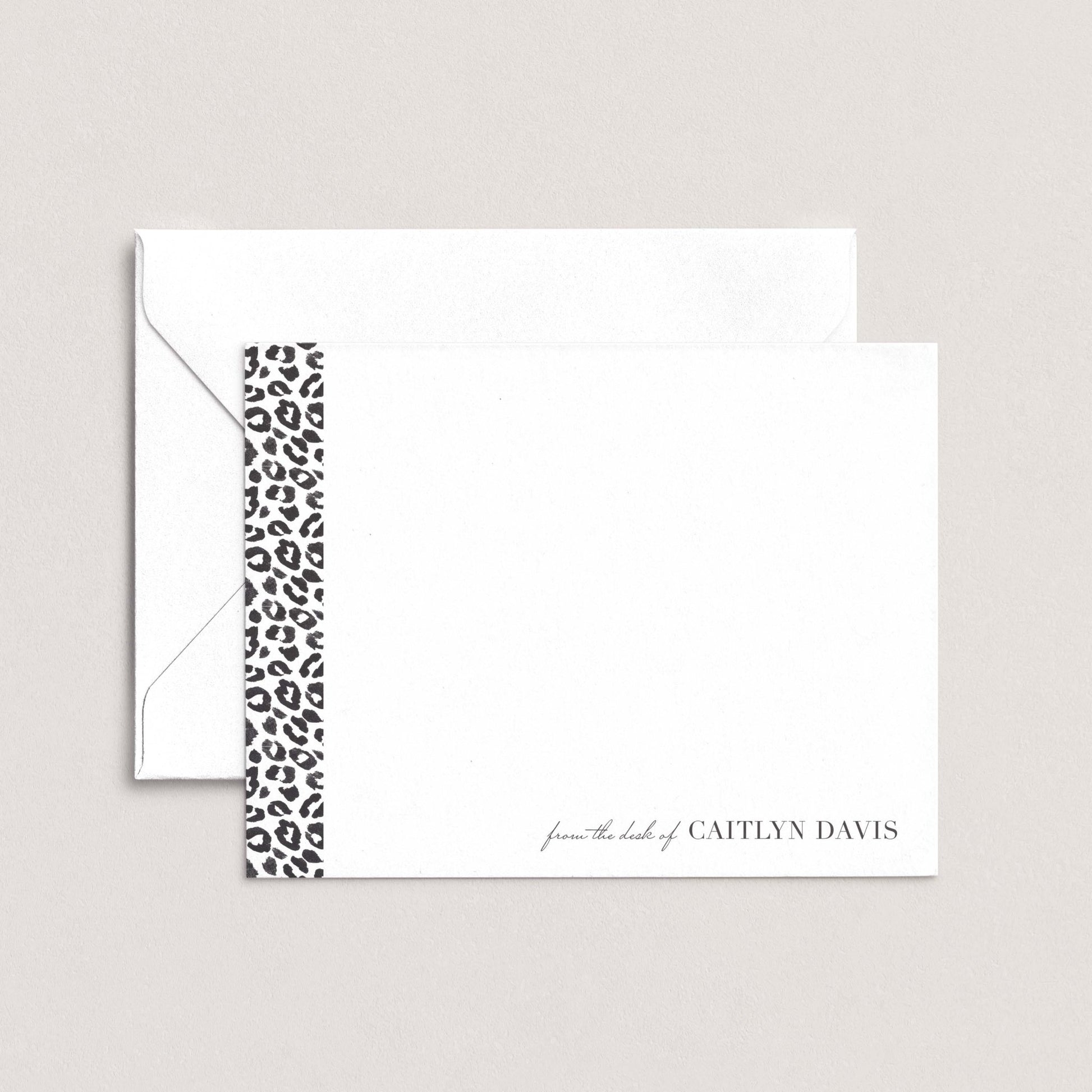 A white envelope with a black and white leopard print border, and a blank card with the name 'Caitlyn Davis' printed on it.