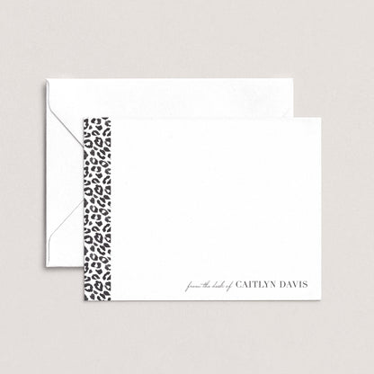 A white envelope with a black and white leopard print border, and a blank card with the name 'Caitlyn Davis' printed on it.