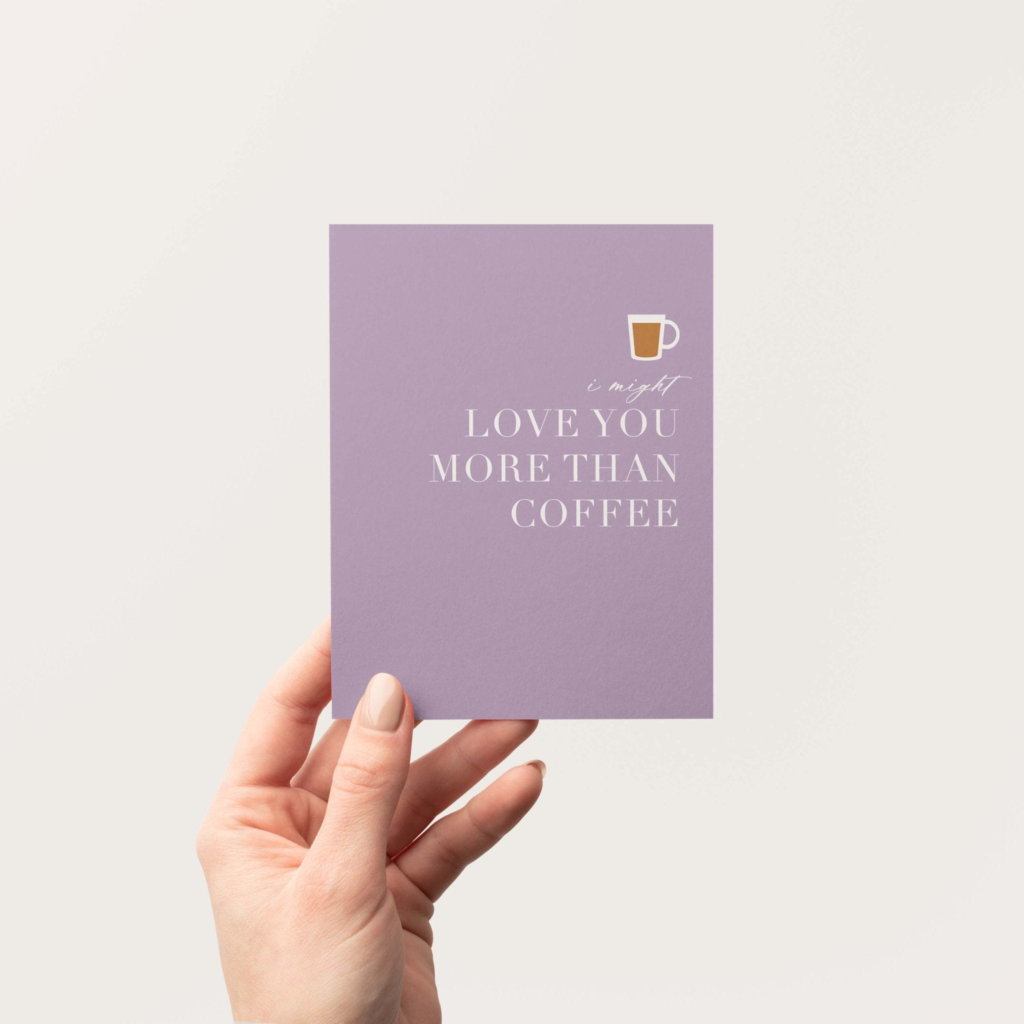 Love You More Than Coffee card by Blú Rose held in hand against a neutral off-white background