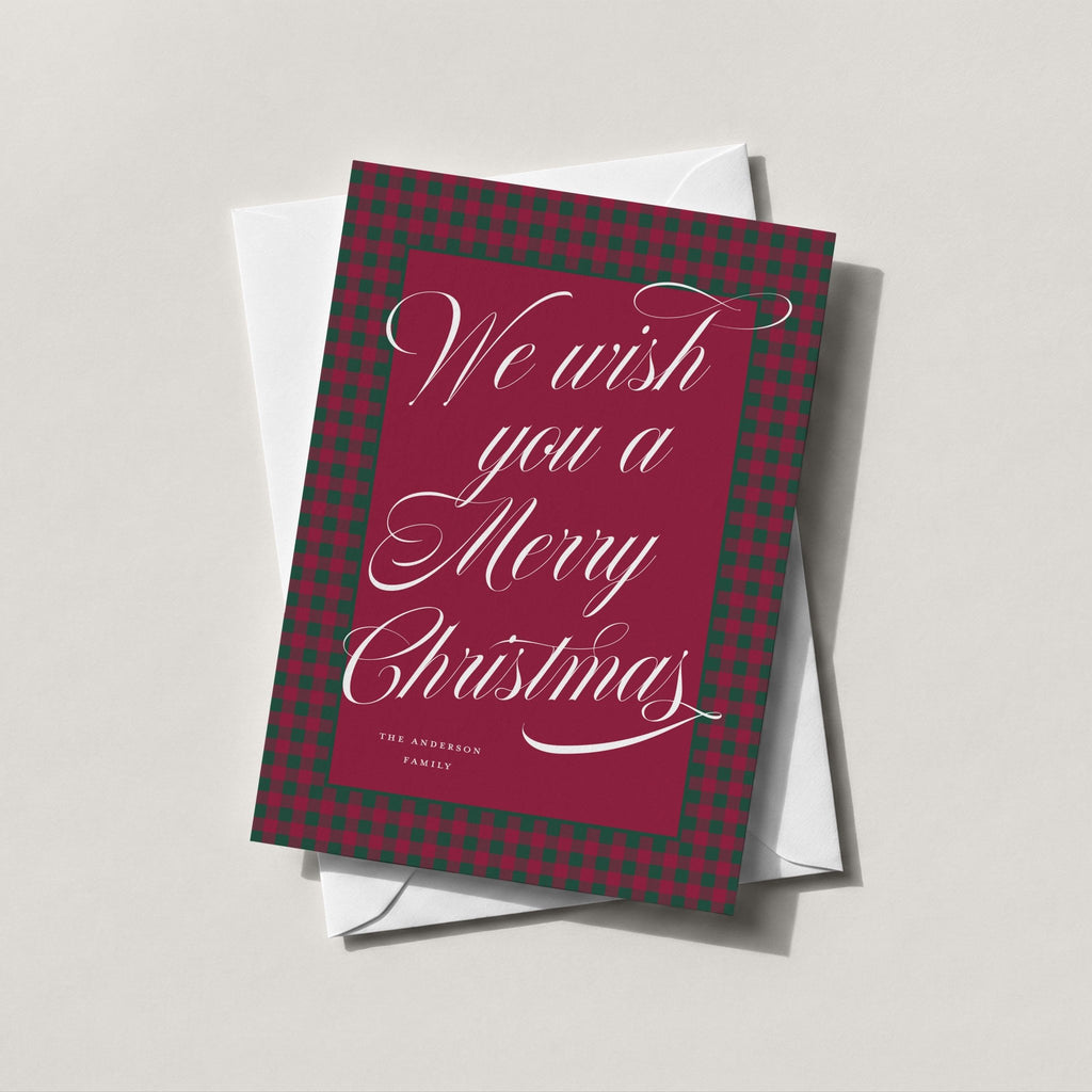 Merry Christmas Plaid holiday card in deep burgundy with white calligraphy reading We wish you a Merry Christmas