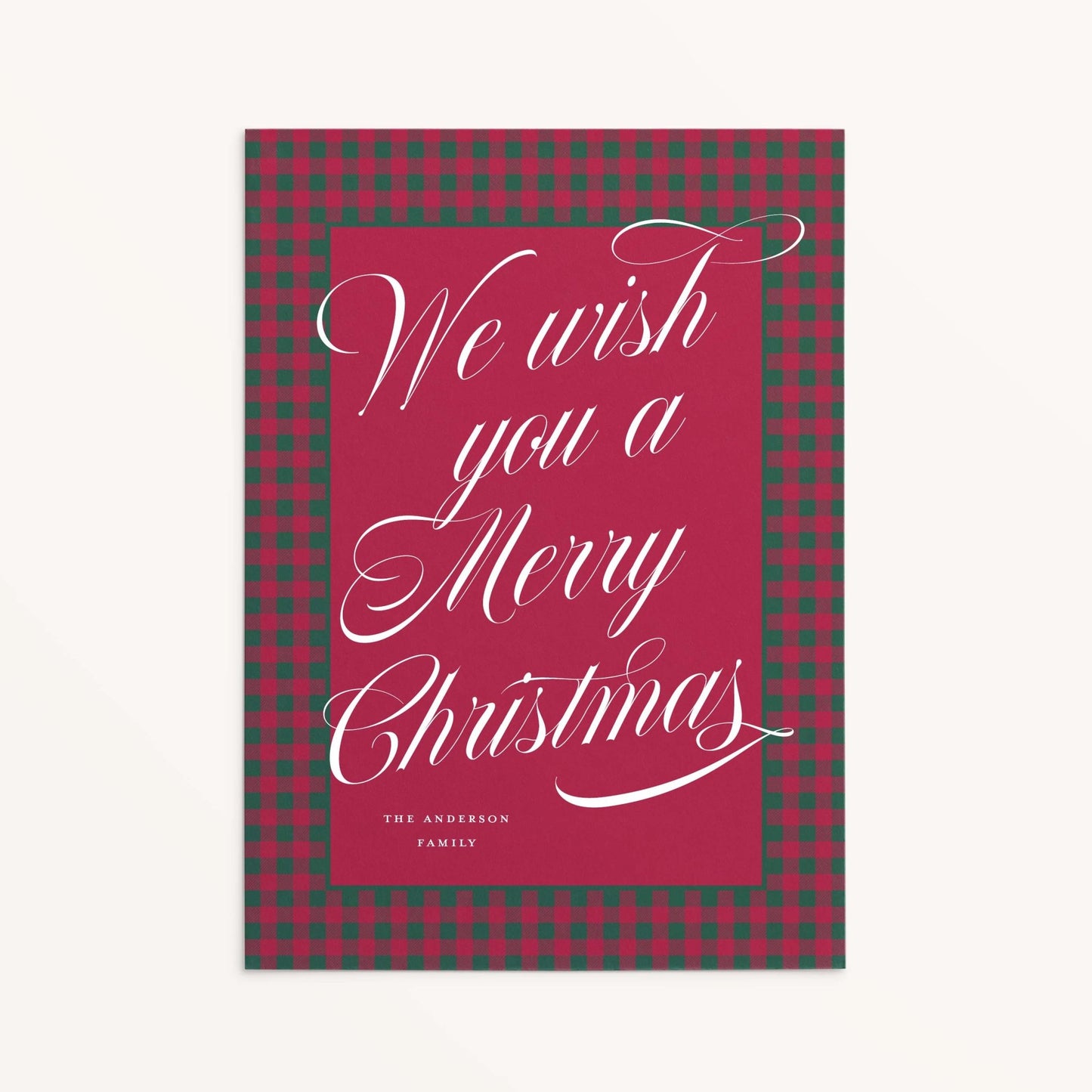 Red and green plaid custom holiday card with white script text reading “We wish you a Merry Christmas."