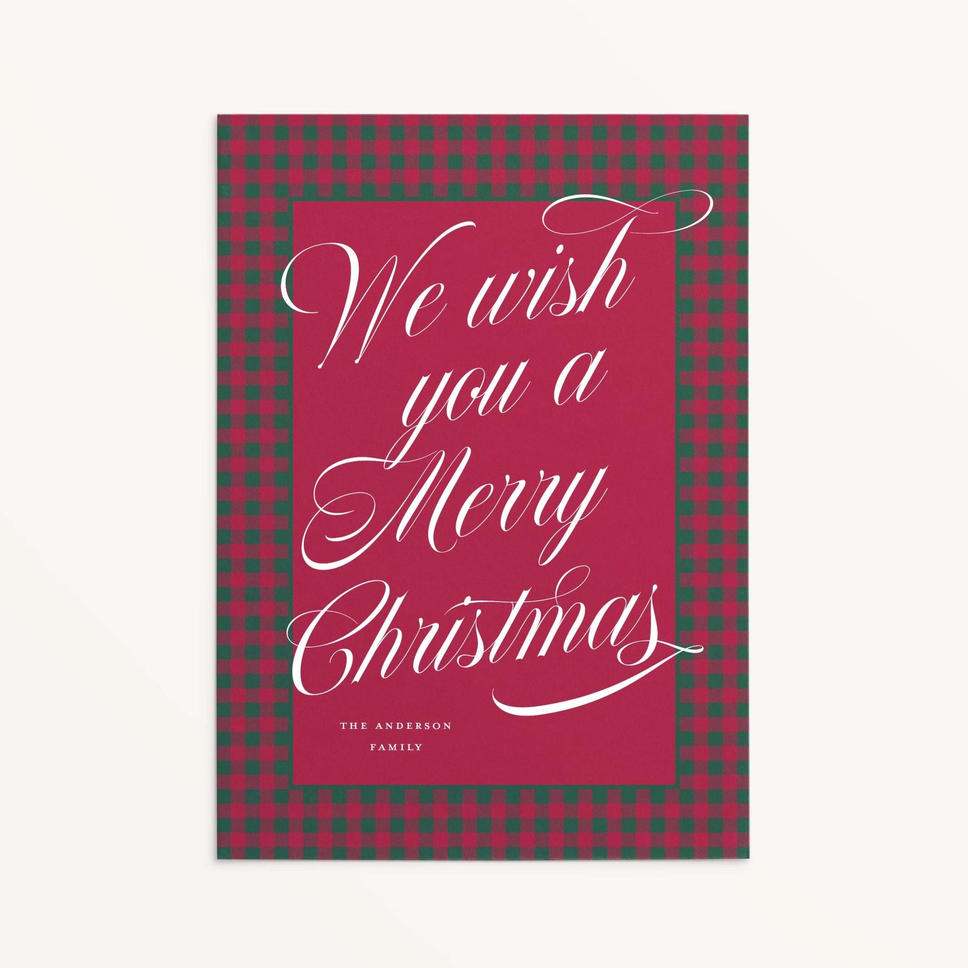 Red and green plaid custom holiday card with white script text reading “We wish you a Merry Christmas."
