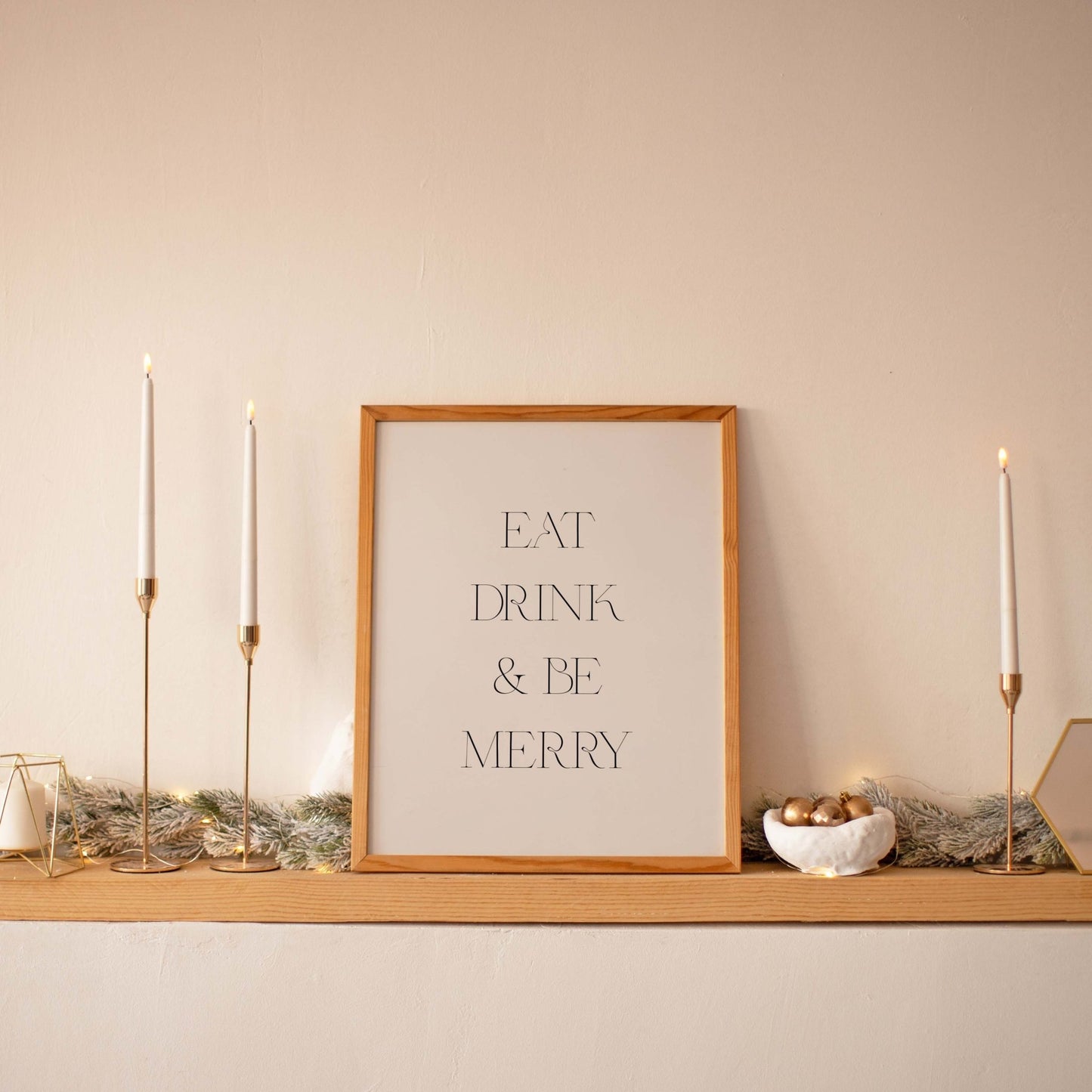 Minimal Eat Drink & Be Merry art print displayed on a shelf with taper candles
