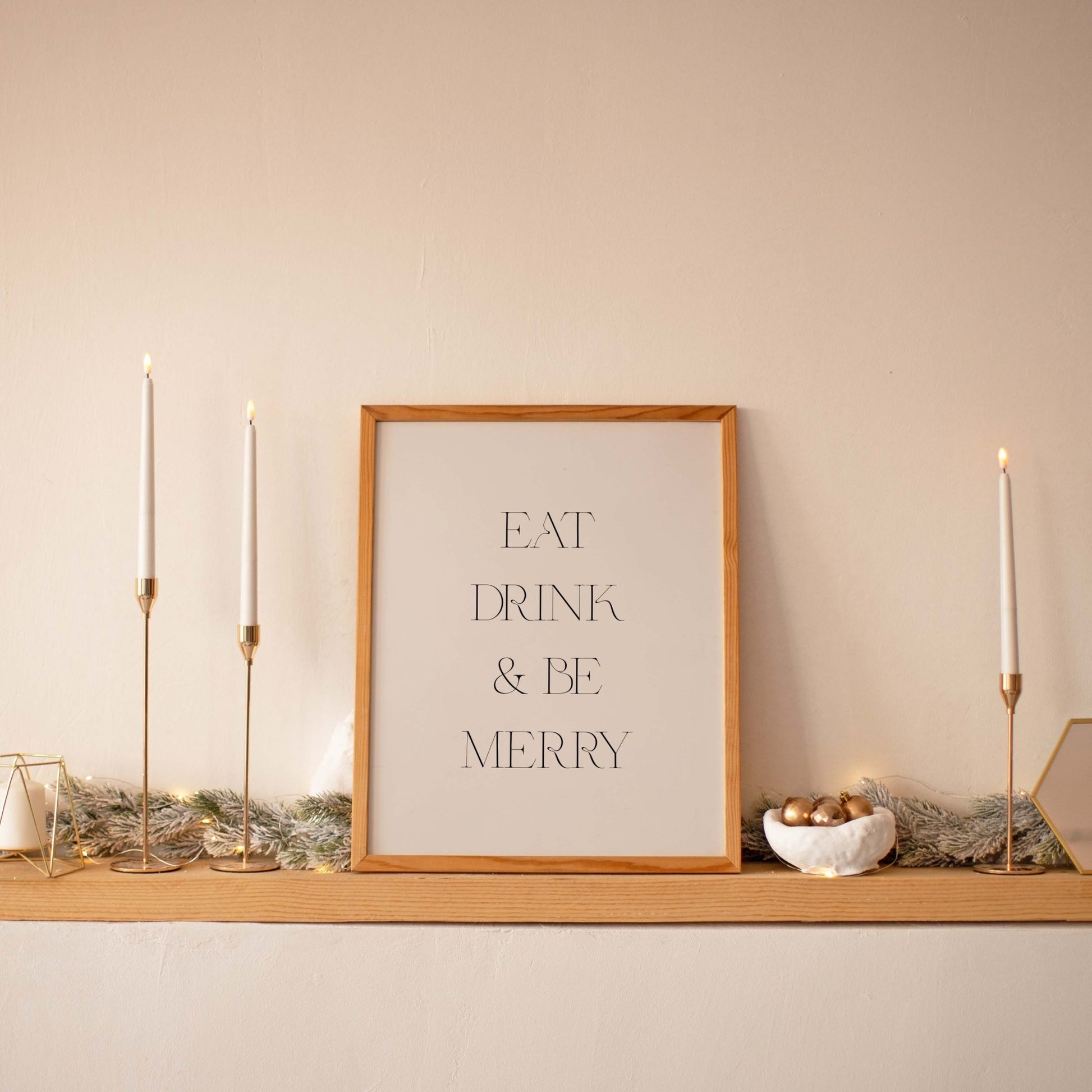 Minimal Eat Drink & Be Merry art print displayed on a shelf with taper candles
