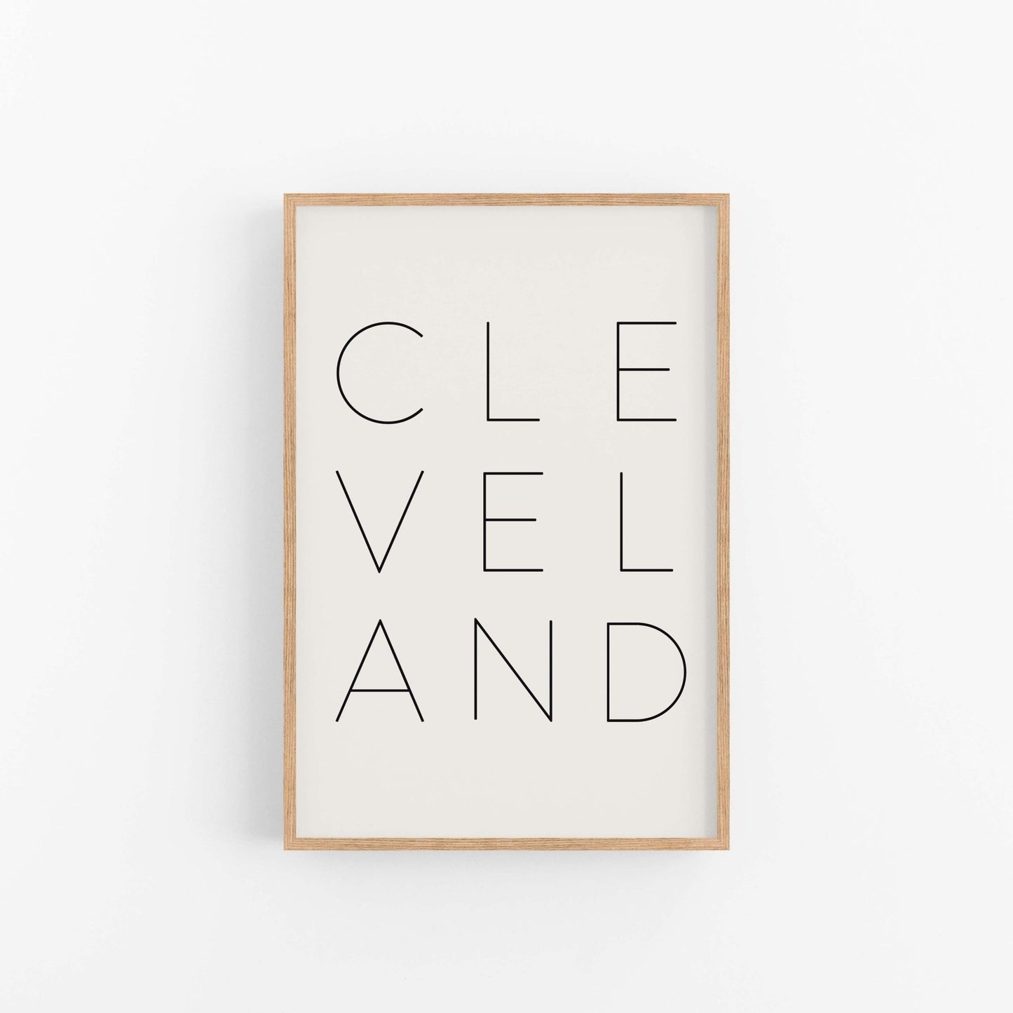 Modern Cleveland wall art print in light wood frame with clean typography design