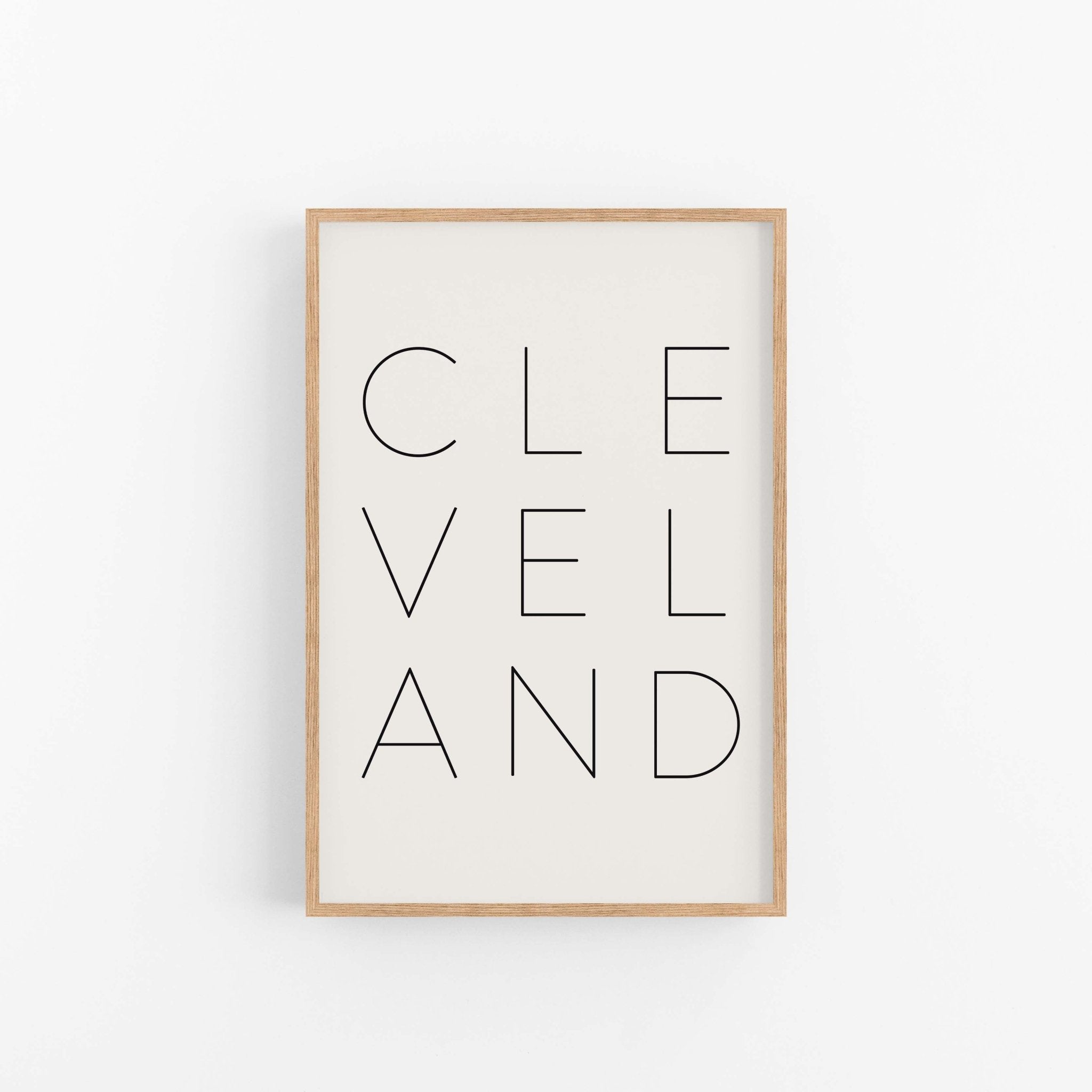 Modern Cleveland wall art print in light wood frame with clean typography design
