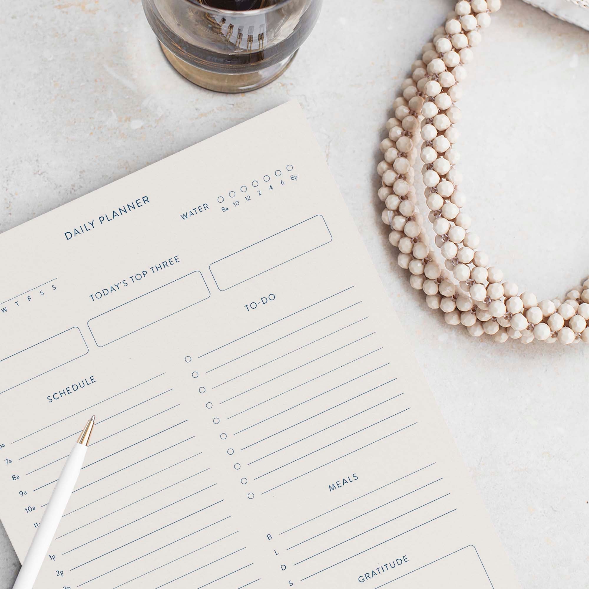 Minimalist Daily Planner notepad by Blú Rose, blank daily planner page styled with a white pen and beaded necklace