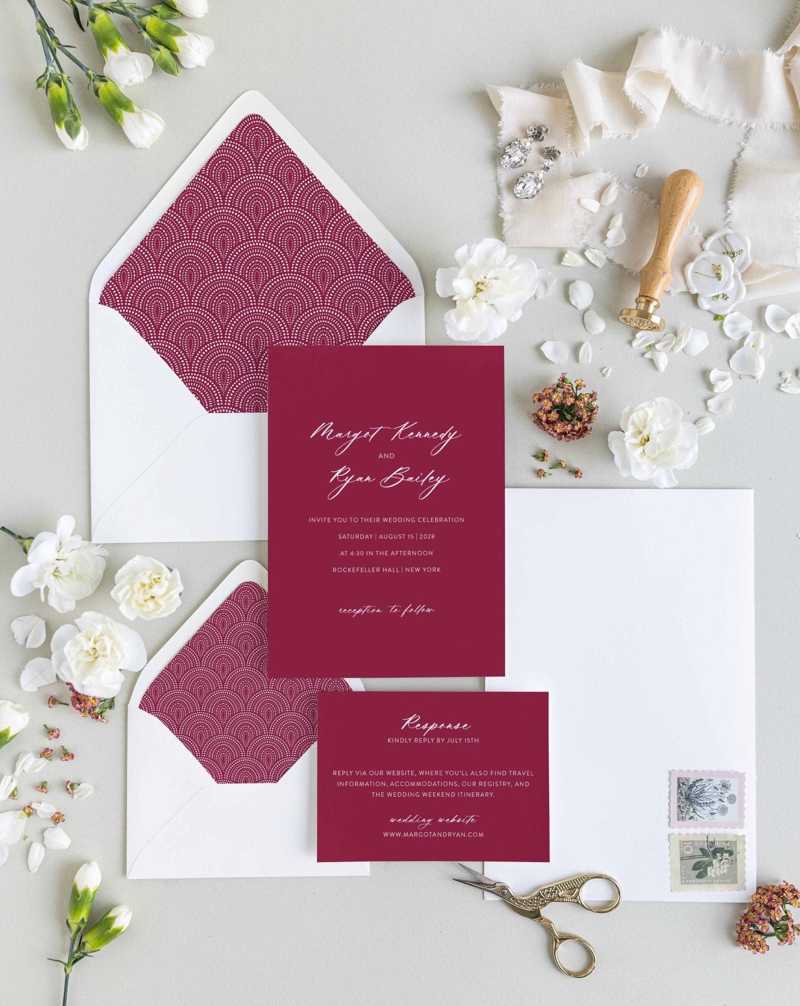 Minimalist Margot wedding invitation suite by Blú Rose, burgundy invitation and response card with white script names, styled with burgundy scallop-lined envelopes, ribbon, and a wax seal