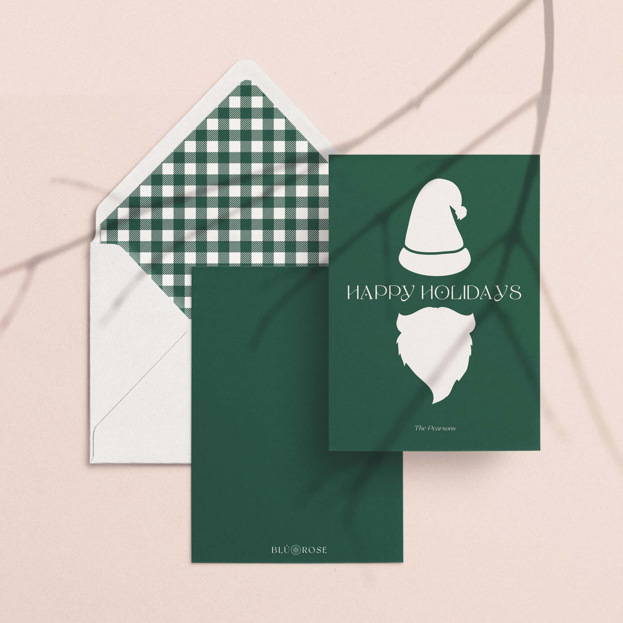 Minimalist Santa card with its green gingham envelope liner styled on a blush backdrop