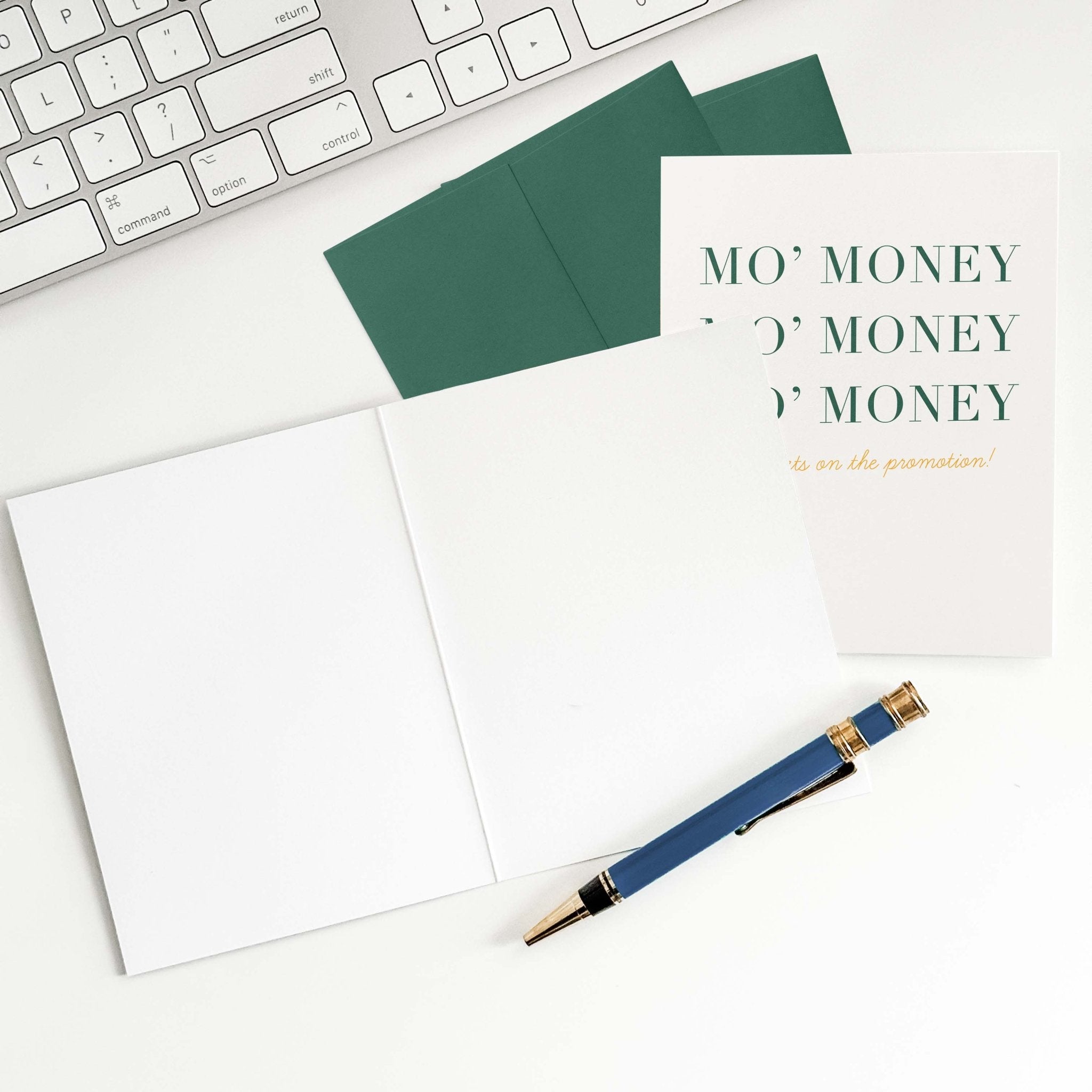 Mo' Money promotion congratulations card by Blú Rose shown open with blank interior, green envelope and pen on a white desk