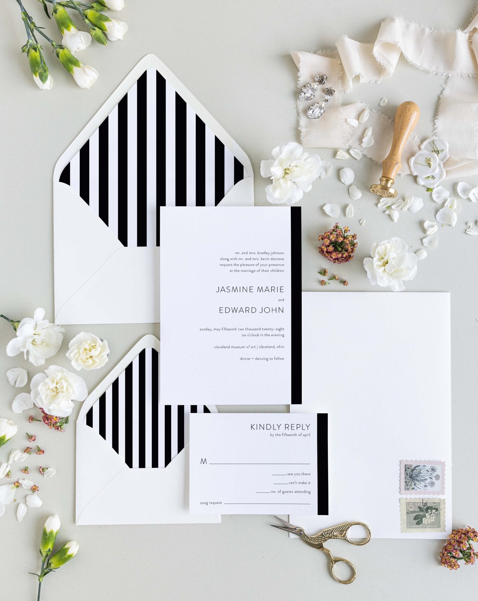 Modern Love wedding invitation suite by Blú Rose, minimalist invitation and reply card with a black side stripe, styled with black-and-white striped envelopes, ribbon, and a wax seal