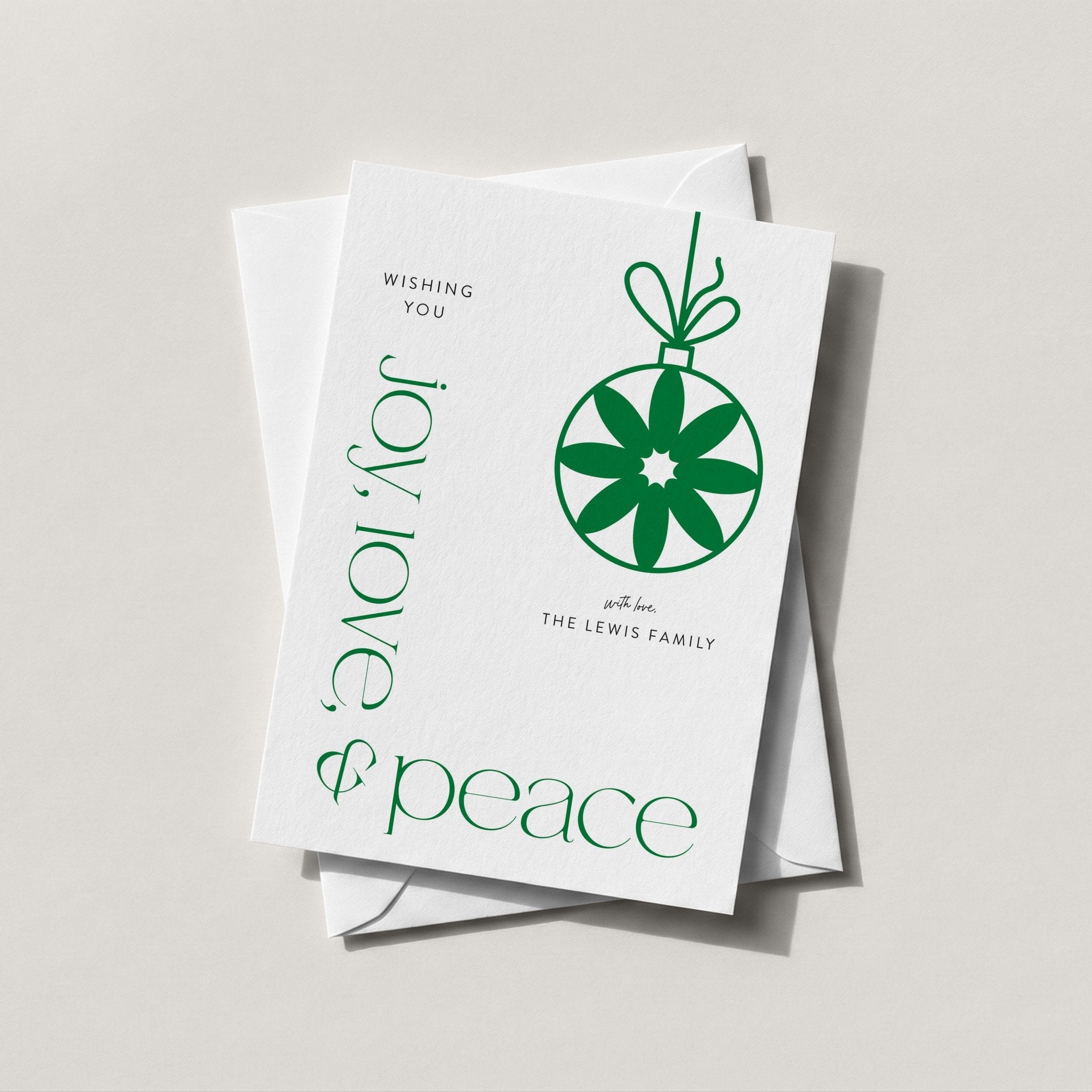 Modern Ornament holiday card with a green snowflake ornament and JOY LOVE & peace lettering