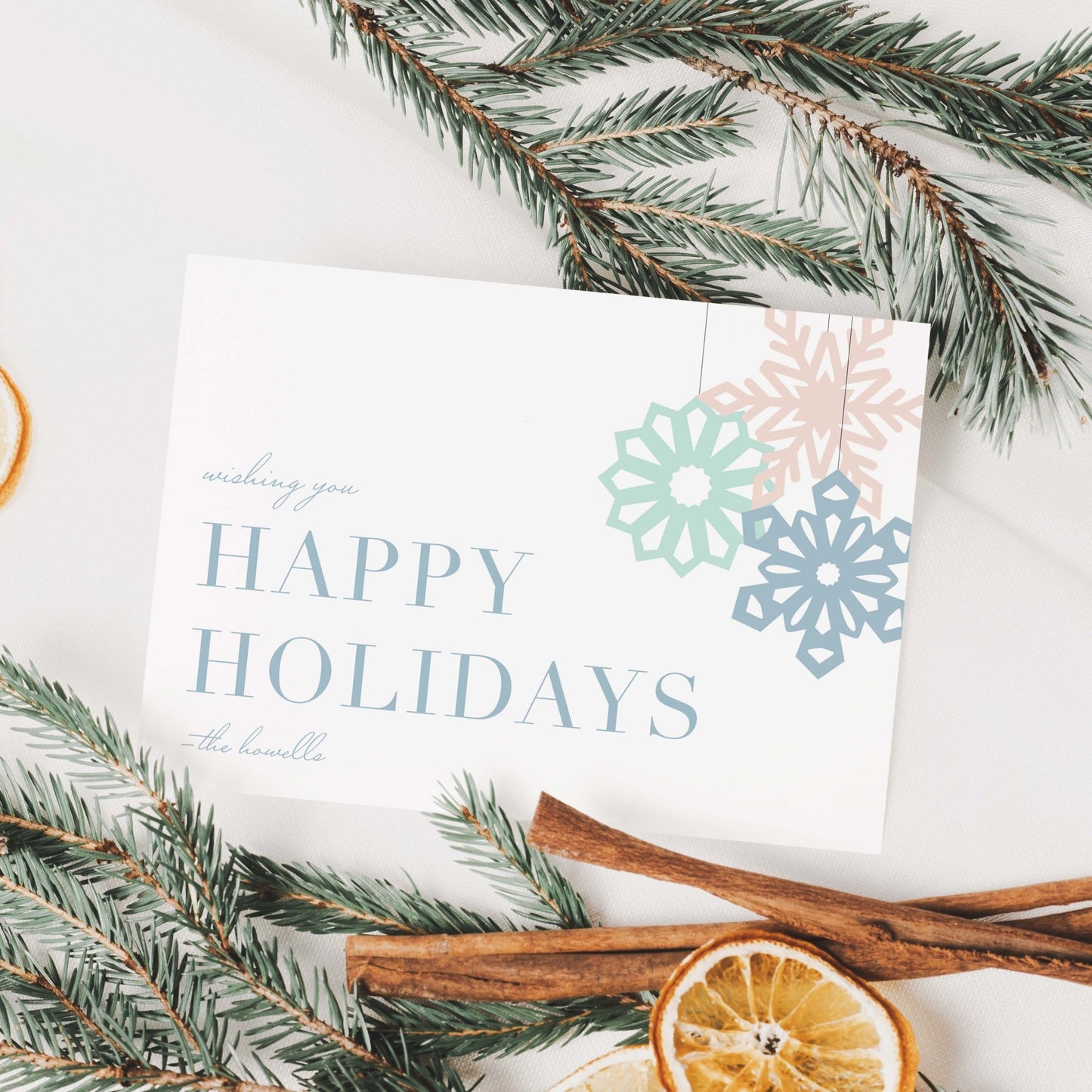 Holiday card displayed with pine branches and dried orange slices for a festive, natural look.