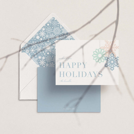 Flat lay of pastel snowflake holiday card and matching envelope liner.
