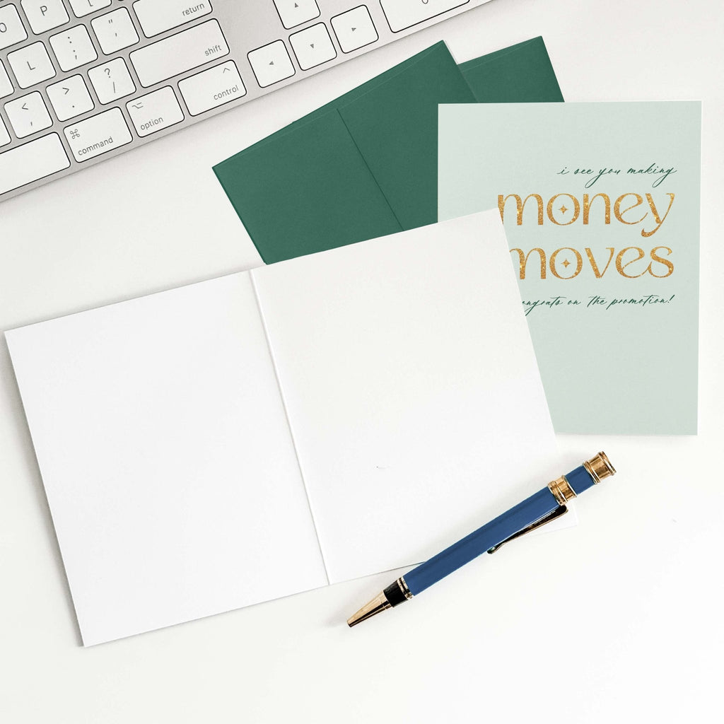 Money Moves promotion congratulations card by Blú Rose shown open with blank interior, green envelope and pen on a white desk
