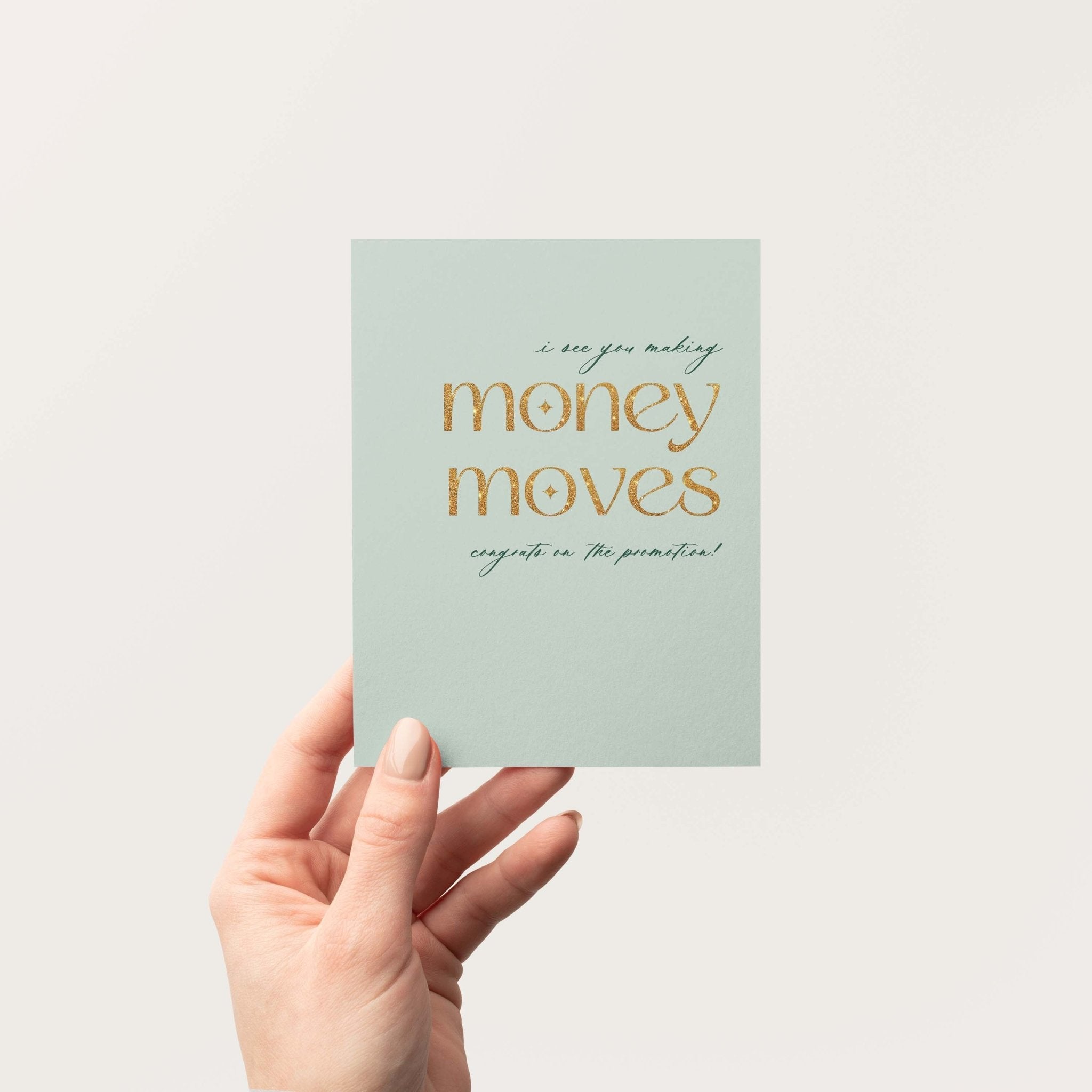 Money Moves congratulations greeting card by Blú Rose held in hand against a neutral off-white background