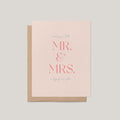 A blush pink greeting card with a kraft brown envelope, featuring the text 'wishing you both MR. & MRS. a happily ever after'