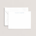 Naomi personalized notecards by Blú Rose, white flat notecard with the name 'Naomi Campbell' in dusty blue, shown with a coordinating white envelope