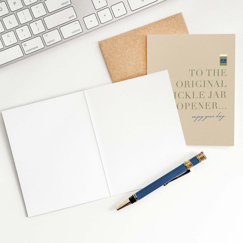 OG Pickle Jar Opener card by Blú Rose shown open with blank interior, kraft envelope and pen on a white desk