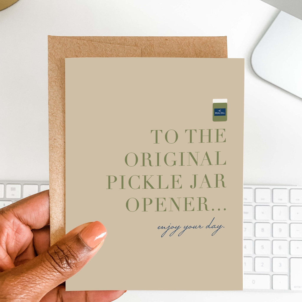 OG Pickle Jar Opener funny dad card by Blú Rose held in hand over a white desk with keyboard and kraft envelope
