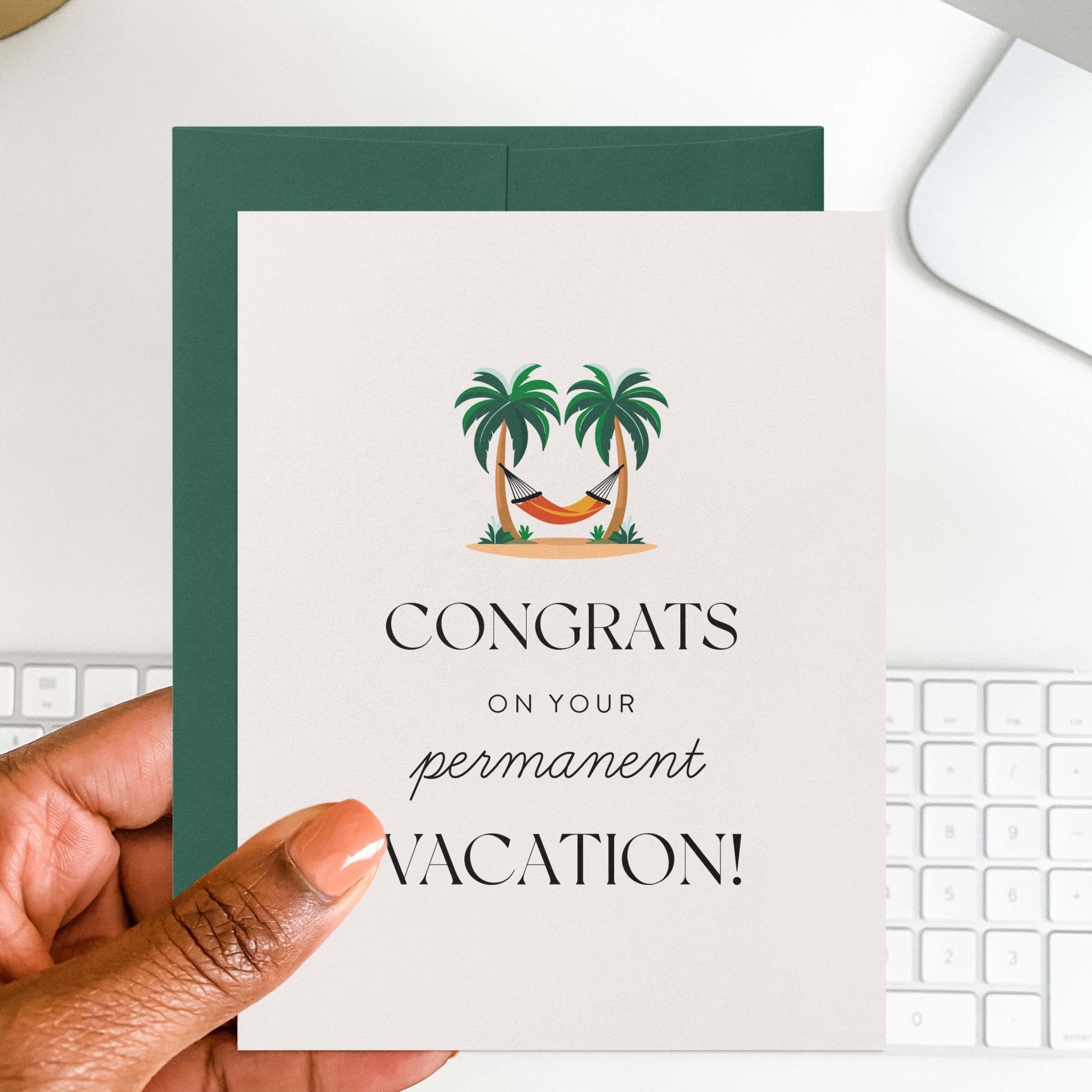 Permanent Vacation retirement card by Blú Rose held in hand over a white desk with keyboard and green envelope
