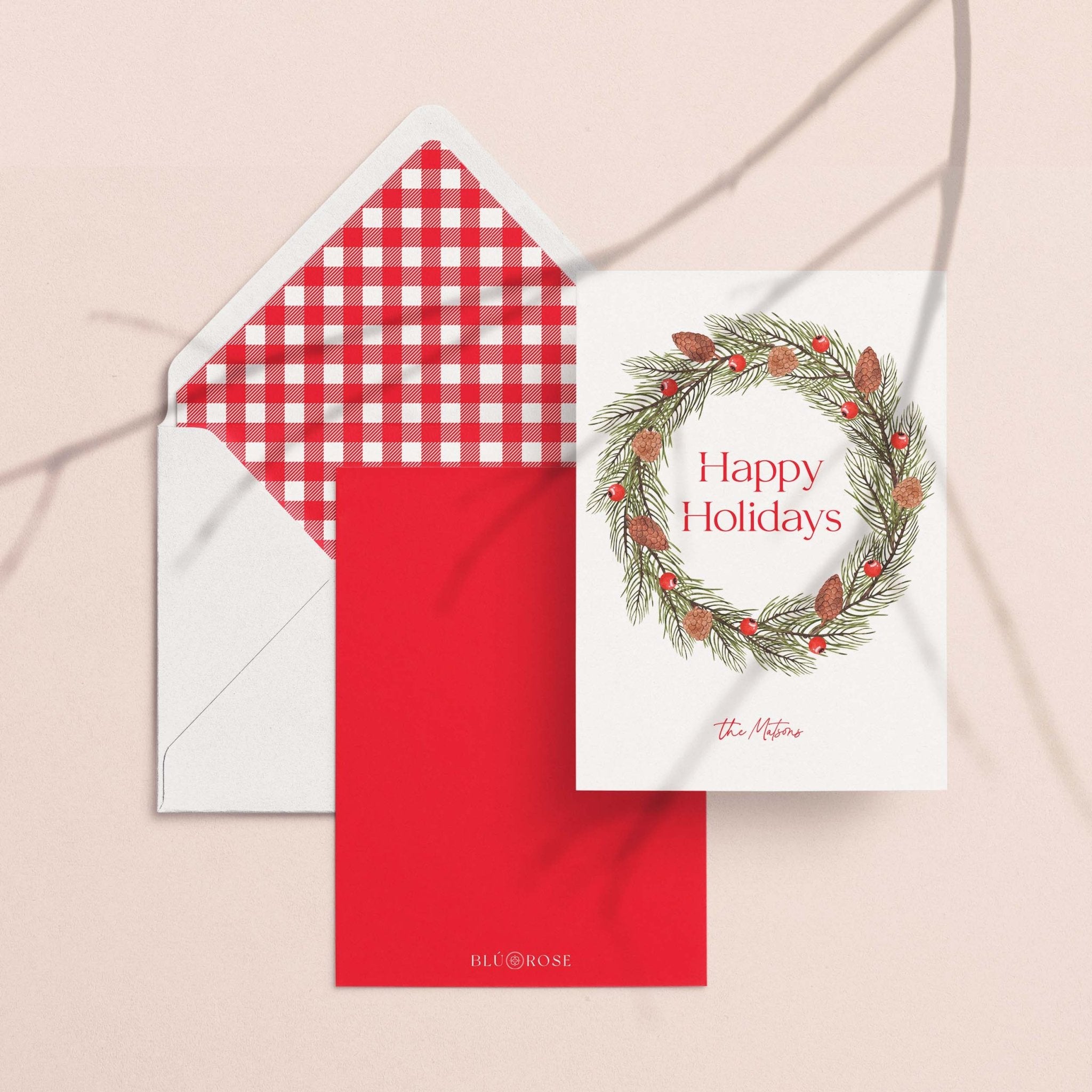 Pinecone Berry Wreath card with its red gingham envelope liner styled on a blush backdrop