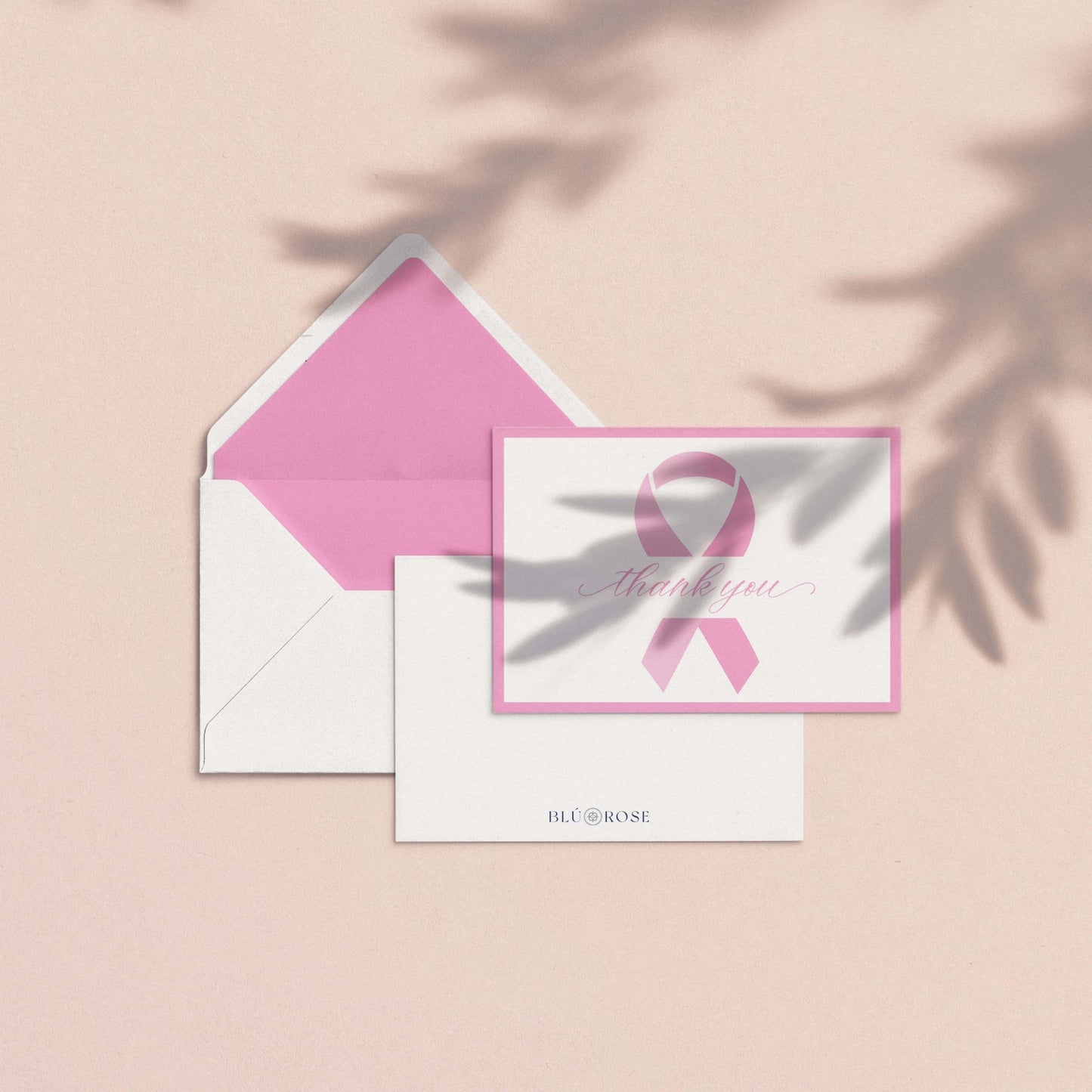Pink Ribbon Thank You Card shown with pink envelope liner and white envelope on a blush background with soft botanical shadows