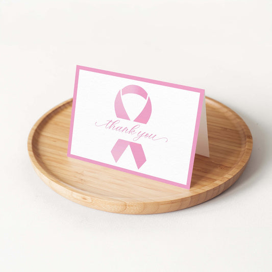 Pink Ribbon Thank You Card by Blú Rose displayed folded on a round bamboo tray