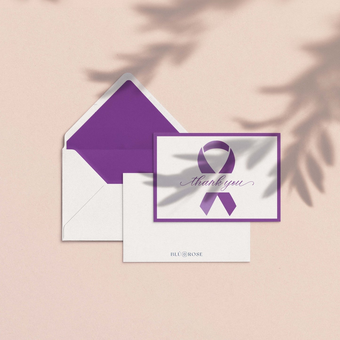 Purple Ribbon Thank You Card by Blú Rose shown with purple envelope liner and white envelope on a blush background with soft botanical shadows