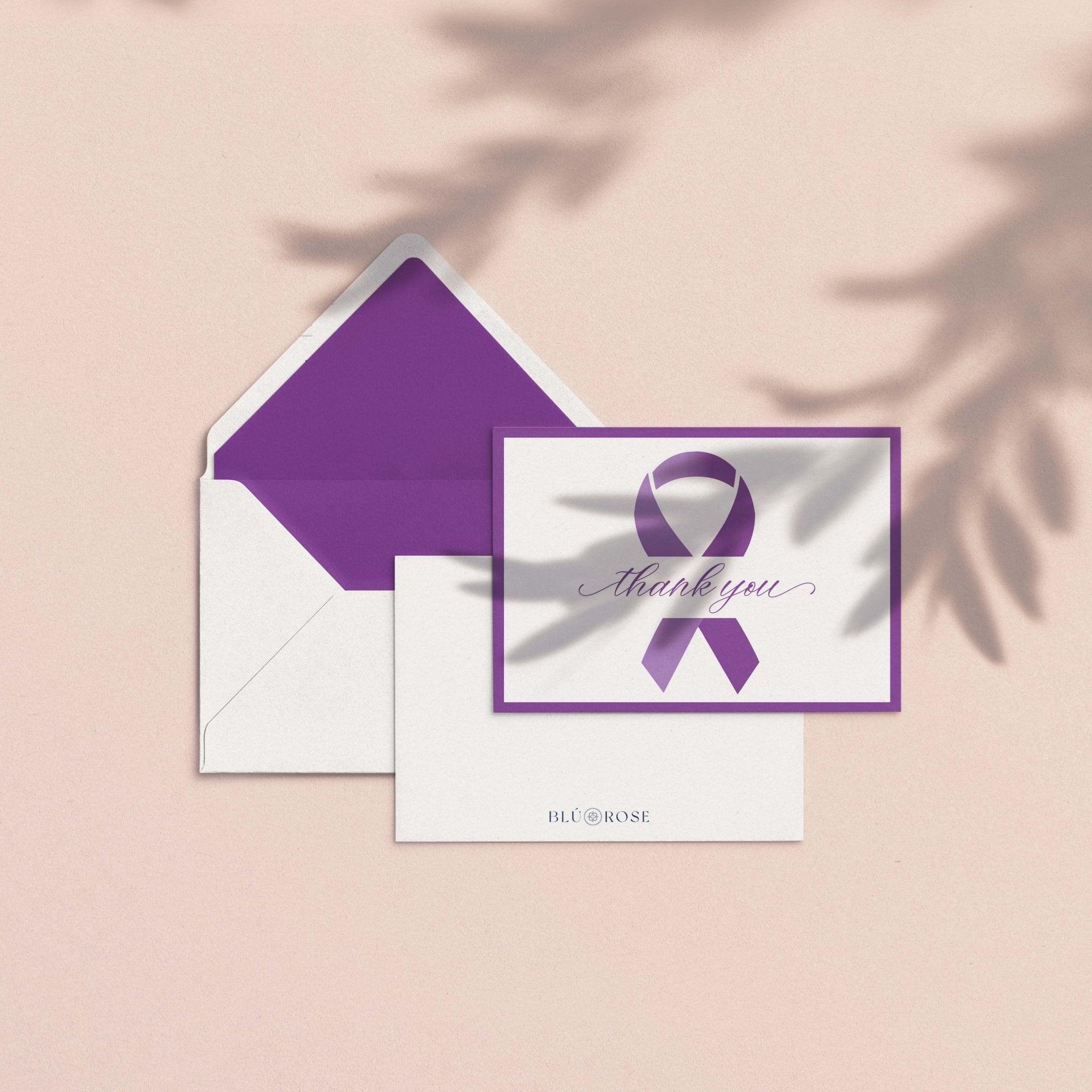 Purple Ribbon Thank You Card by Blú Rose shown with purple envelope liner and white envelope on a blush background with soft botanical shadows