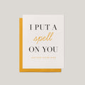 Put a Spell on You Halloween love greeting card by Blú Rose, ivory card with black and gold typography, shown with marigold envelope