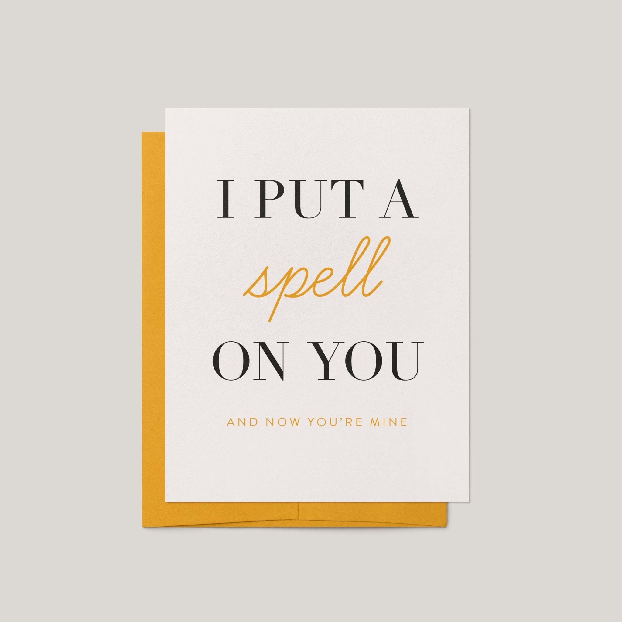 Put a Spell on You Halloween love greeting card by Blú Rose, ivory card with black and gold typography, shown with marigold envelope