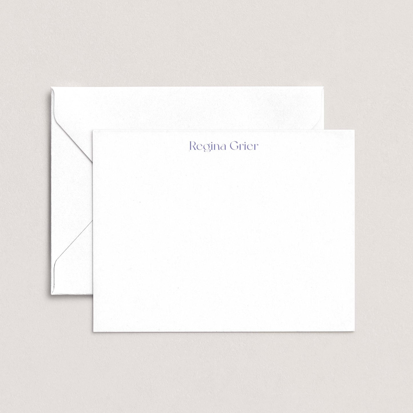 a white envelope and a blank white card with the name "Regina Grier" printed on it.