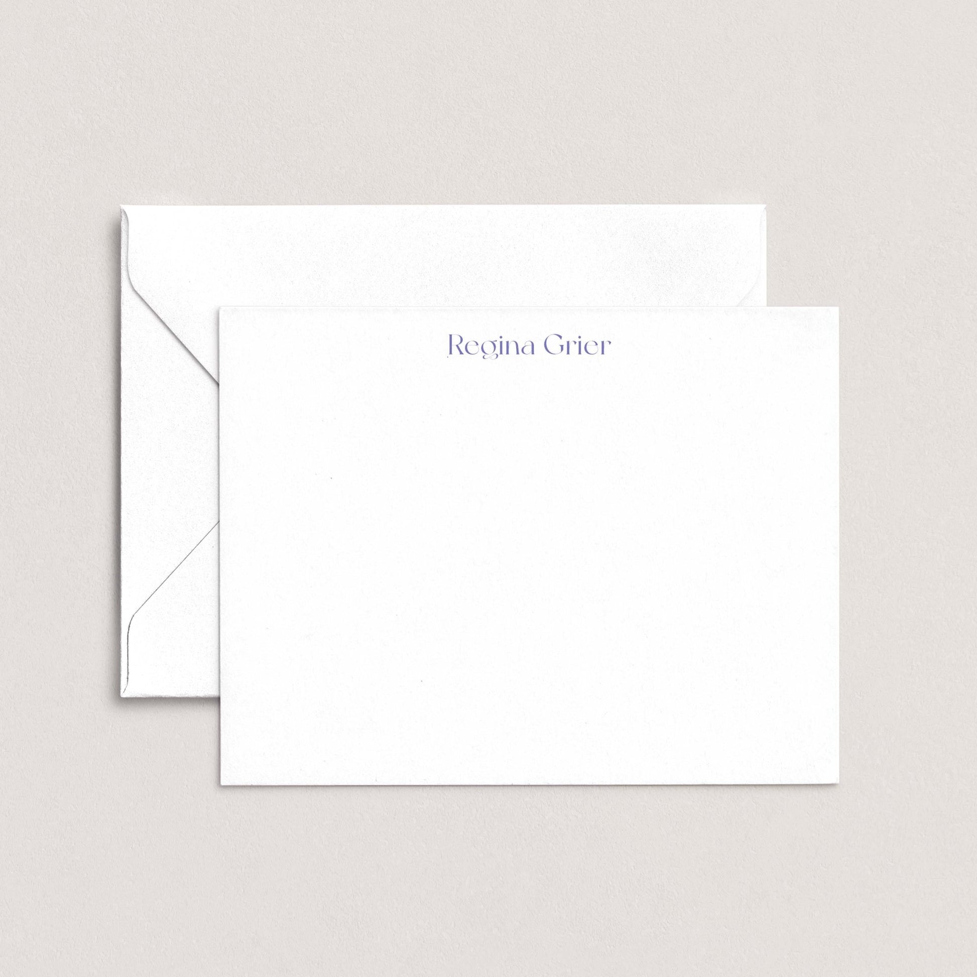 a white envelope and a blank white card with the name "Regina Grier" printed on it.