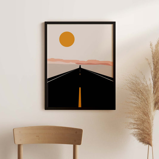 Framed abstract artwork of a sun over a road on a wall with a chair and dried plants.
