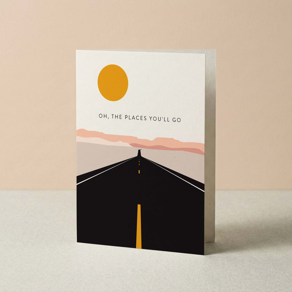 Road Trip graduation card by Blú Rose standing upright, open highway illustration on a neutral background