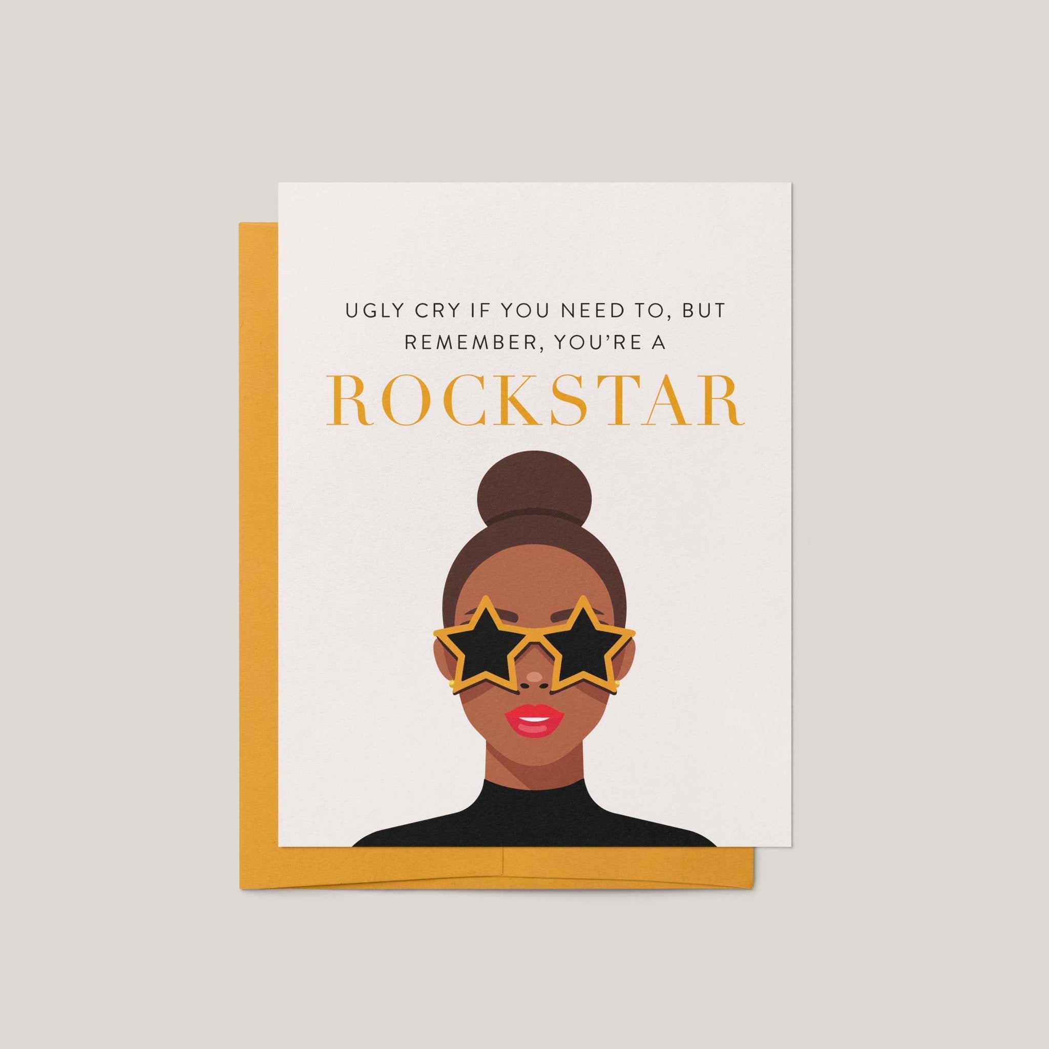 Rockstar encouragement greeting card by Blú Rose, illustration of a woman in gold star sunglasses with you're a rockstar text, shown with marigold envelope